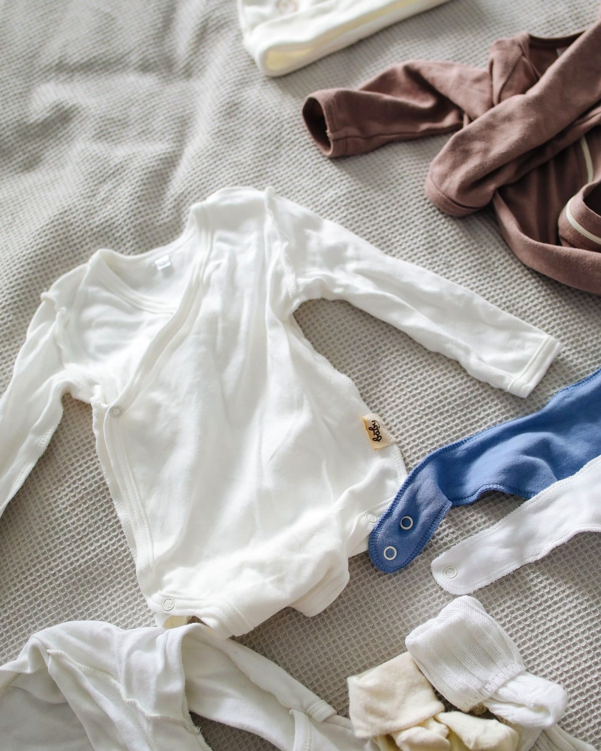Bodies e peças brancas de bebê dobradas