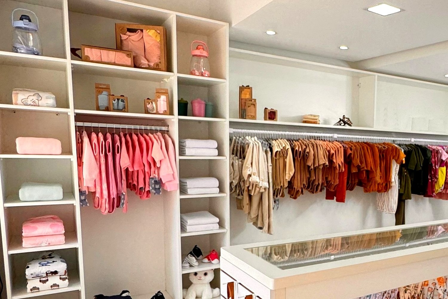 Loja de roupas infantis com prateleiras brancas e araras de peças coloridas
